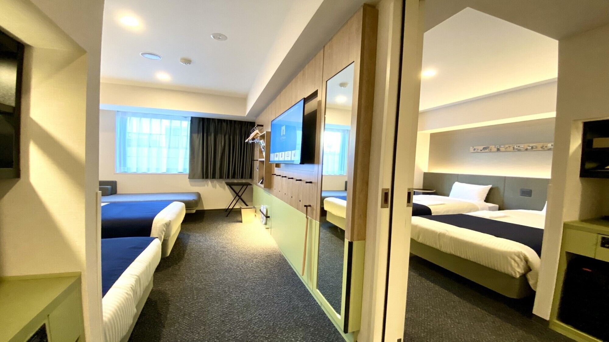 A hotel room with two beds, a TV, a desk, and a window.