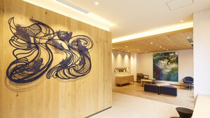 A modern interior with a wooden wall, a large abstract painting, and a seating area with a wooden floor. - hotel MONday Premium Ueno Okachimachi (Tokyo)