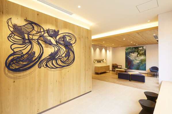 A modern interior with a wooden wall, a large abstract painting, and a seating area with a wooden floor. - hotel MONday Premium Ueno Okachimachi (Tokyo)