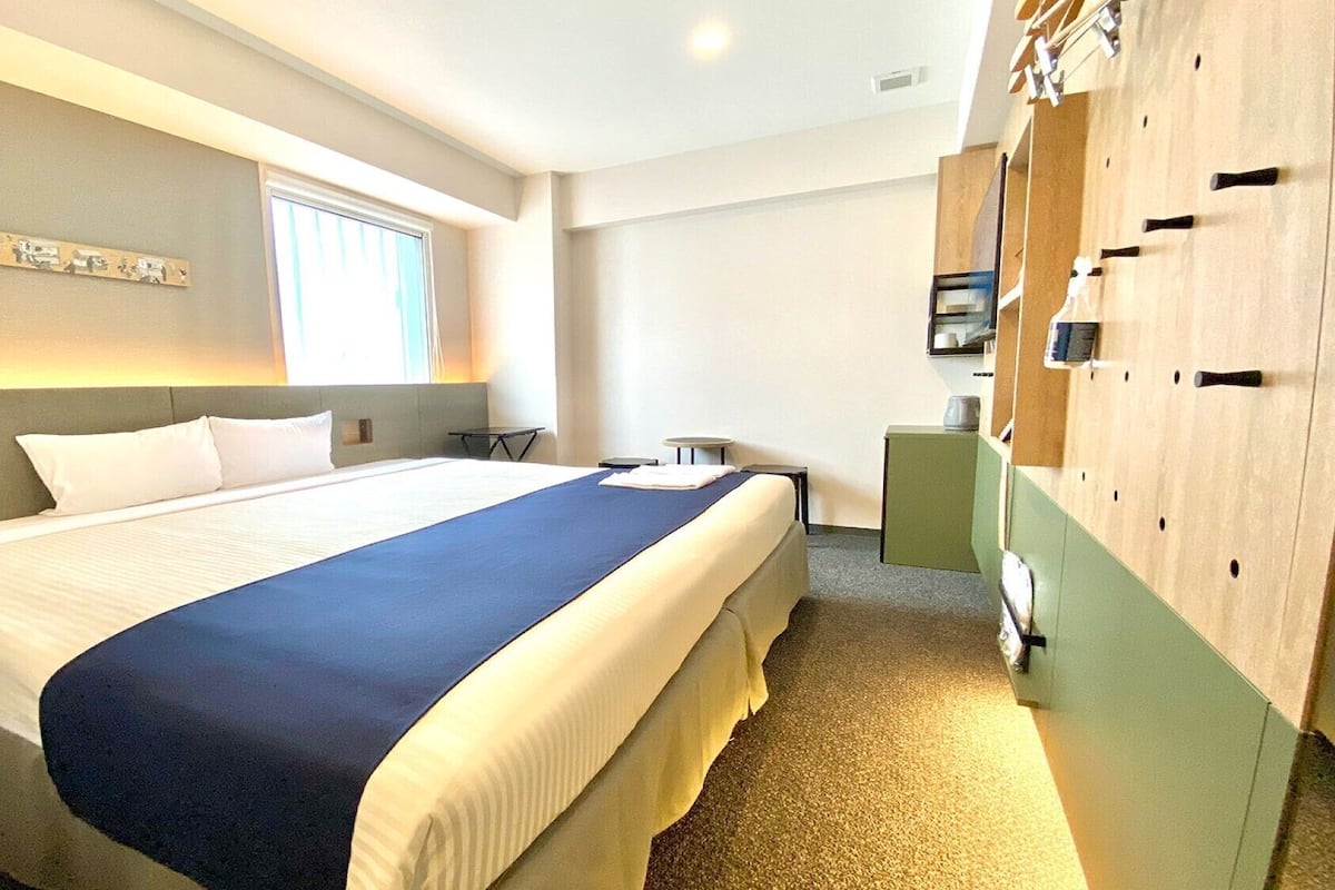 Ein Hotelzimmer mit einem großen Bett, einem Schreibtisch, einem Kleiderschrank und einem Fenster.