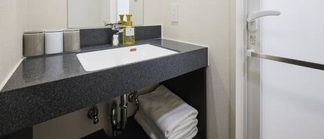 A bathroom with a white sink, a mirror, a towel rack, and a toilet.
