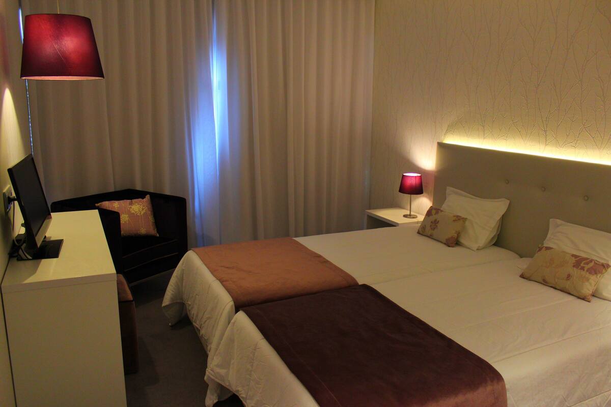Una habitación de hotel con cama, escritorio, silla y lámpara.