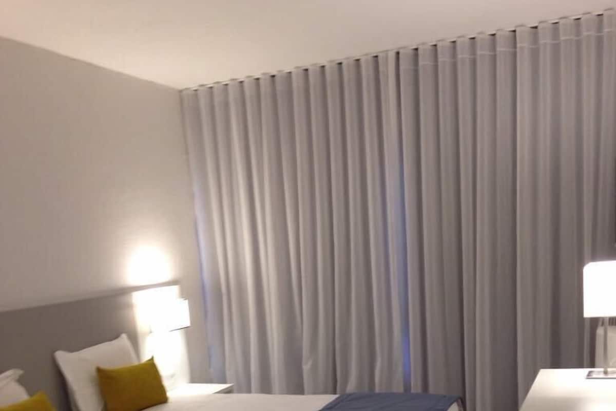 Una habitación de hotel con una cama grande, dos mesitas de noche y un escritorio.