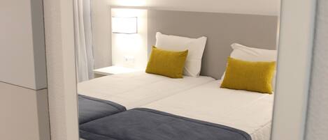 A modern hotel room with a large bed, a bedside table, and a lamp.