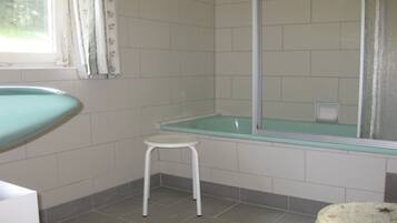 A bathroom with a bathtub, a small stool, and a toilet.