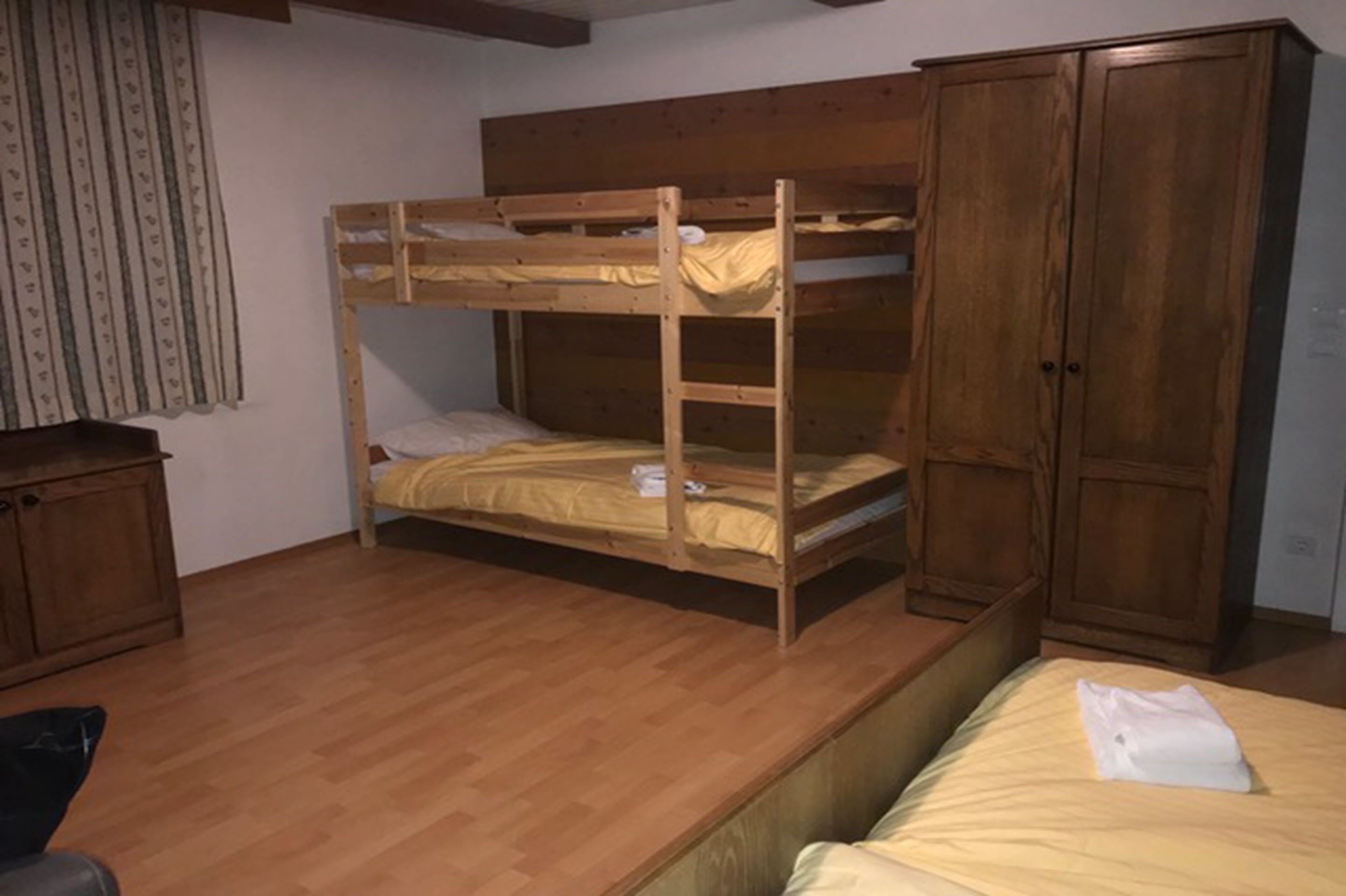 Ein Stockbett mit einem Holzkopfende, einem Kleiderschrank und einem kleinen Schrank.