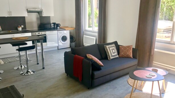 Een moderne woonruimte met een bank, een eettafel, een keuken en een wasmachine.
