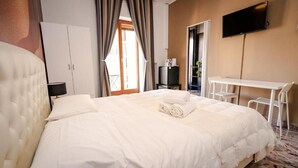 Habitación de hotel con una cama grande, un escritorio, un televisor y un armario.