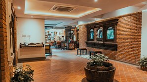 A spacious lobby with a brick wall, a large planter with plants, and a reception desk. - Hotel Thamel House (Kathmandu)