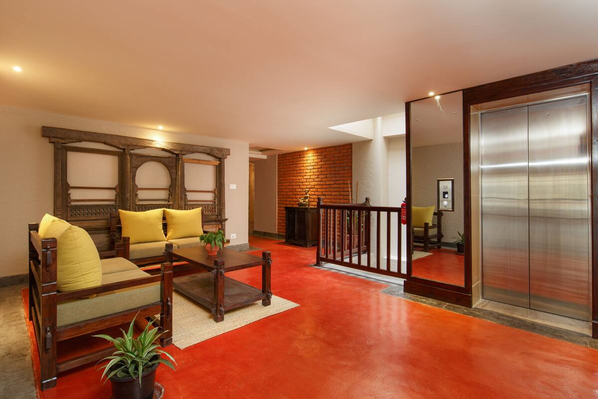 A spacious living area with a red floor, a wooden sofa set, a coffee table, and a brick wall.
