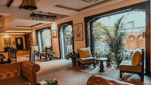 A lobby with leather sofas, a coffee table, and potted plants. - Hotel Thamel House (Kathmandu)