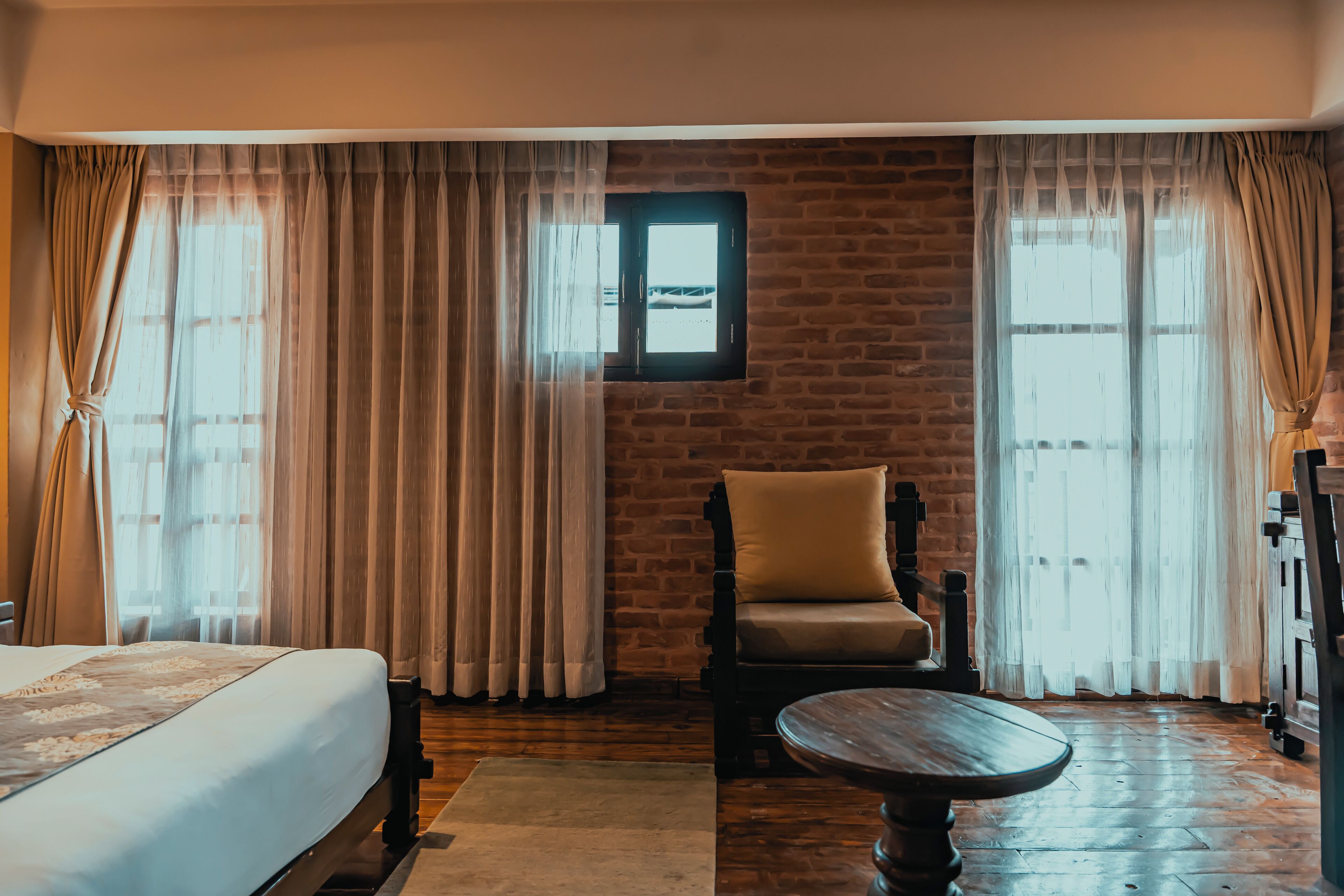Een hotelkamer met een bed, een stoel, een tafel en een raam met gordijnen.