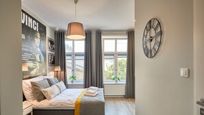 Une chambre à coucher moderne avec un lit, une grande horloge murale et une affiche.
