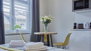 Une chambre d’hôtel avec un lit, une petite table ronde ornée d’un vase de fleurs, une chaise, un four à micro-ondes et une bouilloire posée sur le comptoir.