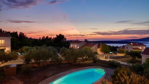 Bairro residencial com casas, piscina e céu ao pôr do sol.