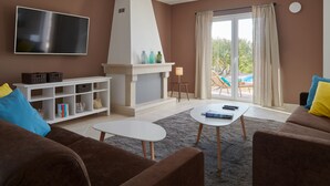 Uma sala de estar com lareira, televisão de tela plana e sofá.