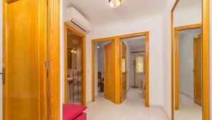 A hallway with wooden doors, a pink bench, and a ceiling light fixture. - Villa Canta House only 60 meter to the beach (Playa de Muro)