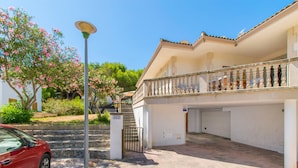 A two-story building with a balcony, a car parked in front, and a street lamp. - Villa Canta House only 60 meter to the beach (Playa de Muro)