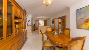 A dining area with a wooden table and chairs, a cabinet with glass doors, and a painting on the wall. - Villa Canta House only 60 meter to the beach (Playa de Muro)