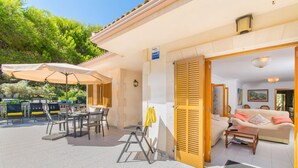 An outdoor seating area with tables and chairs, a sofa inside, and a door leading to the interior. - Villa Canta House only 60 meter to the beach (Playa de Muro)