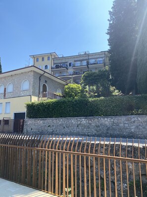 A multi-story building with stone walls, balconies, and a stone fence in the foreground. - Leonardo Walsh Apartment With Lake View (Torri del Benaco)