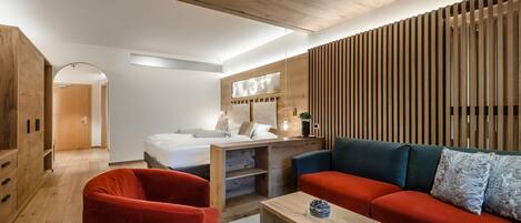 A modern room with a wooden ceiling, a red sofa, a wooden table, and a bed with a wooden headboard.