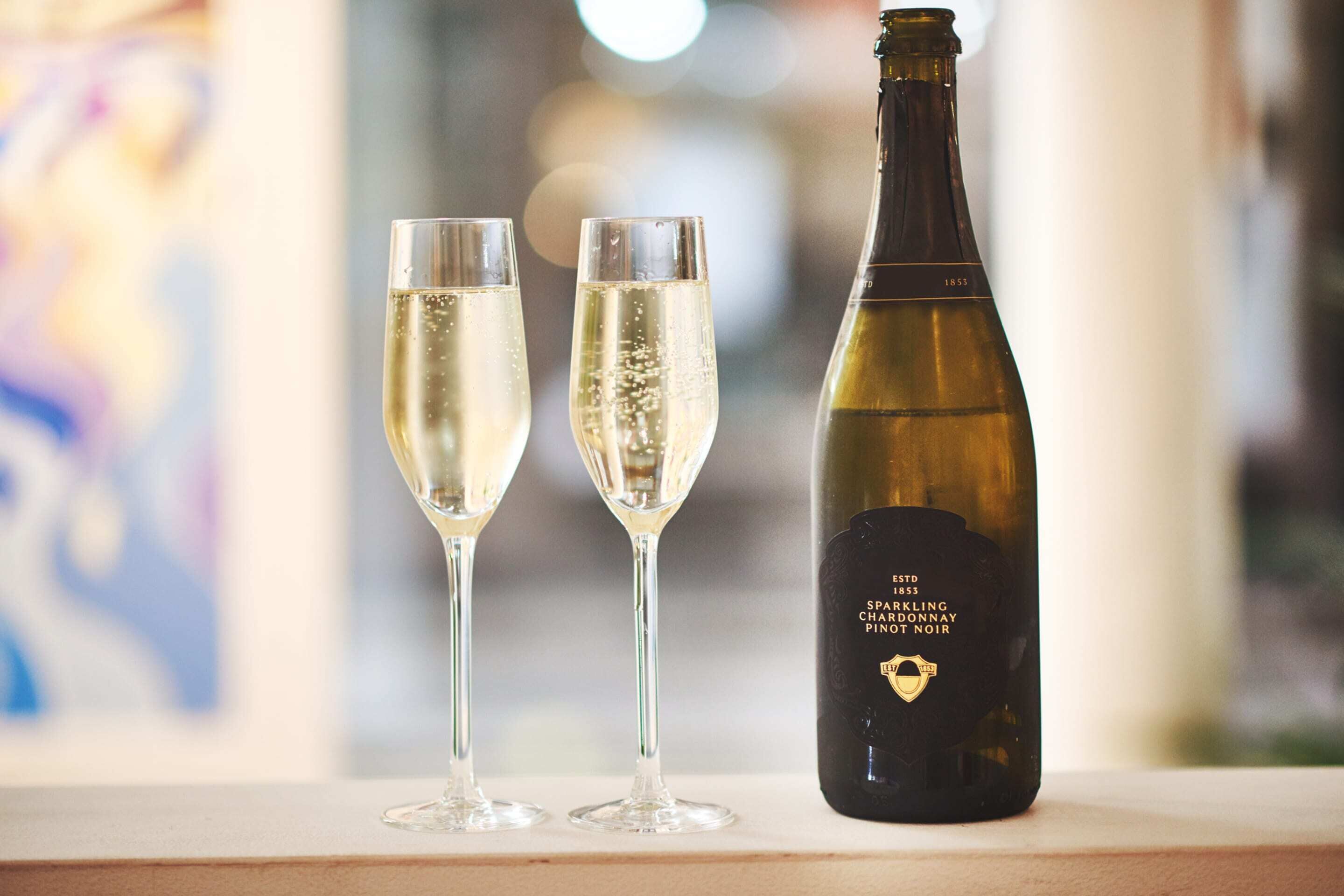 Two champagne flutes and a bottle of 1855 sparkling champagne.
