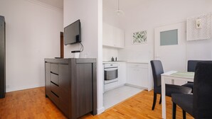 A modern kitchen with white cabinets, a built-in oven, and a dining area with a table and chairs. - Plac Konstytucji Studio (Warsaw)