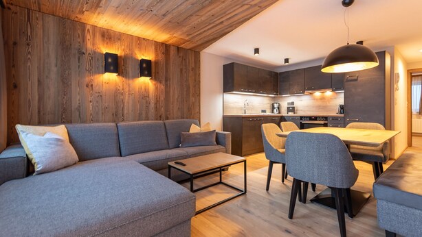 Uma sala de estar moderna com sofá seccional, uma mesa de centro e um espaço de jantar com cadeiras e mesa.