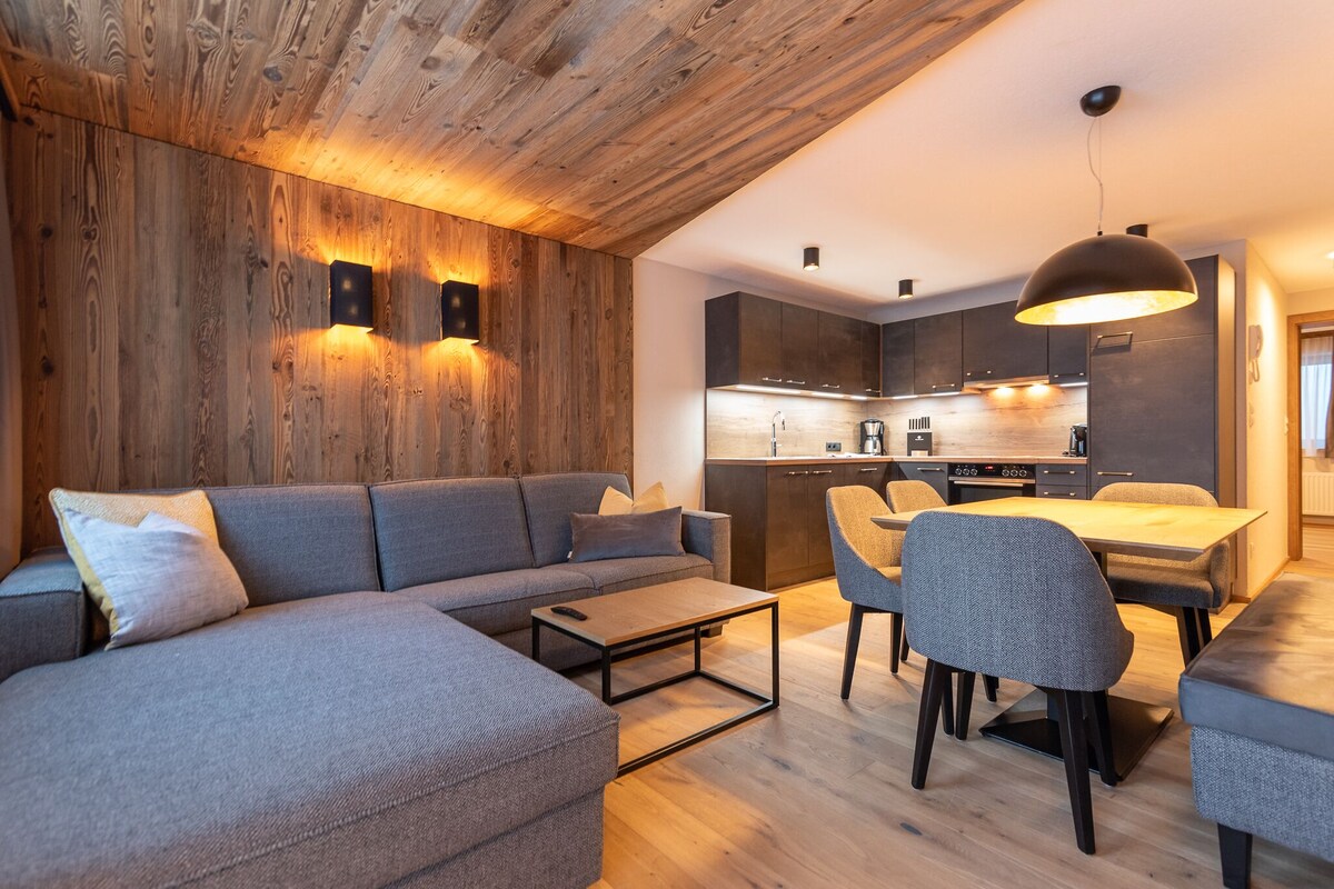 A modern living room with a sectional sofa, a coffee table, and a dining area with chairs and a table.