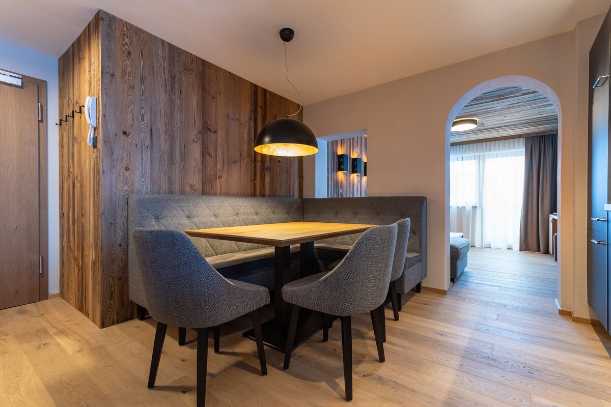A modern dining area with a wooden accent wall, a table with four chairs, and a pendant light.