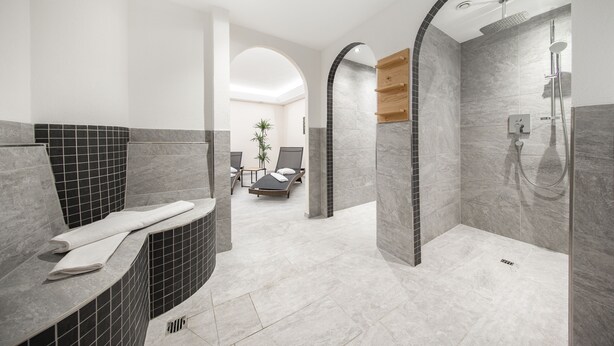 Un baño moderno con ducha curva, bañera y zona de estar con una planta.