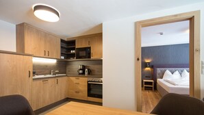 Una cocina compacta con armarios de madera, horno empotrado y una mesa de comedor con sillas.