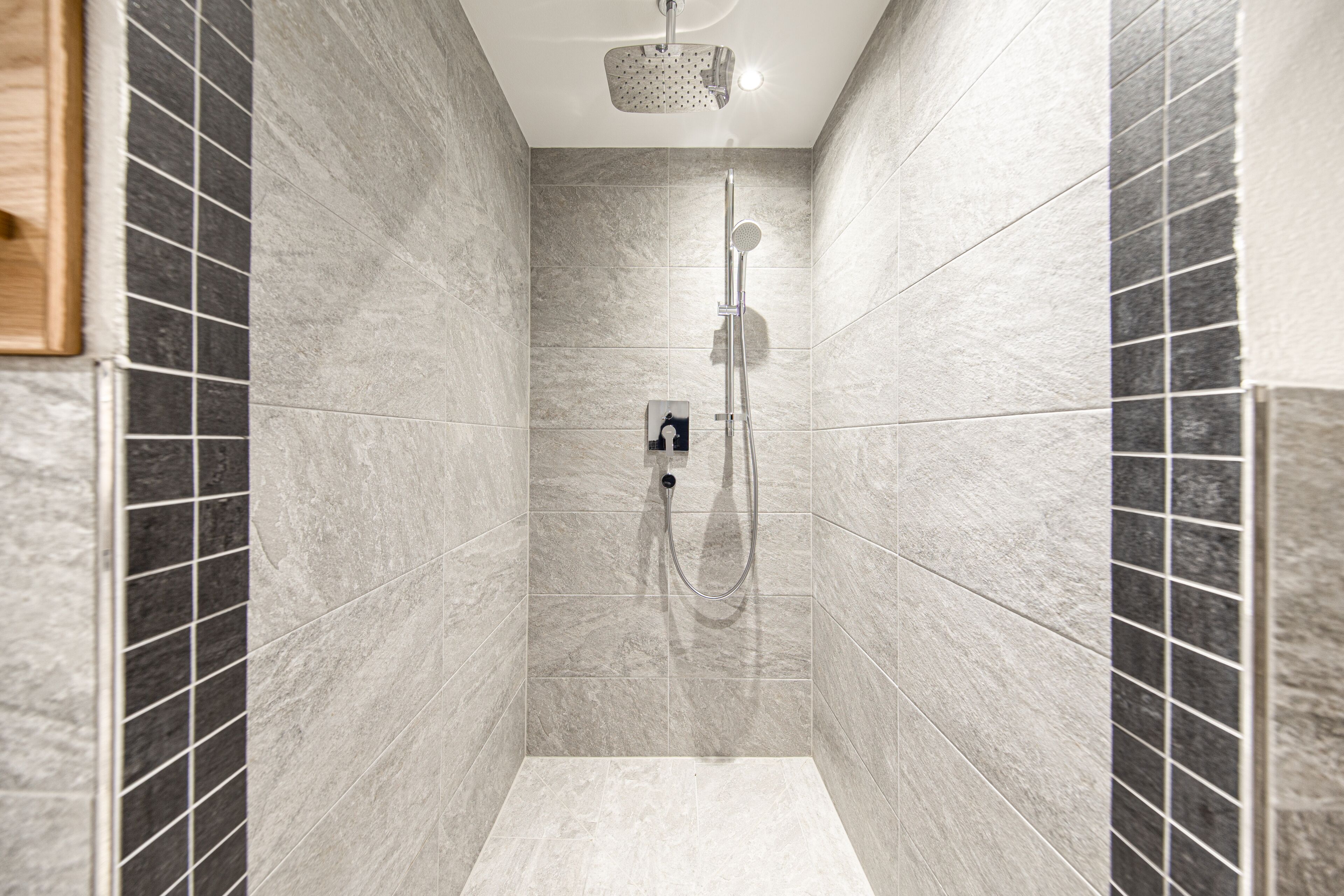 A modern shower with a handheld showerhead and a wall-mounted faucet.