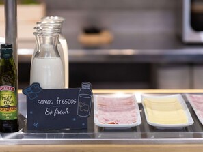 Una presentación de alimentos con una botella de leche, un cartel que dice "Somos frescos So fresh" y varios platos de carne.