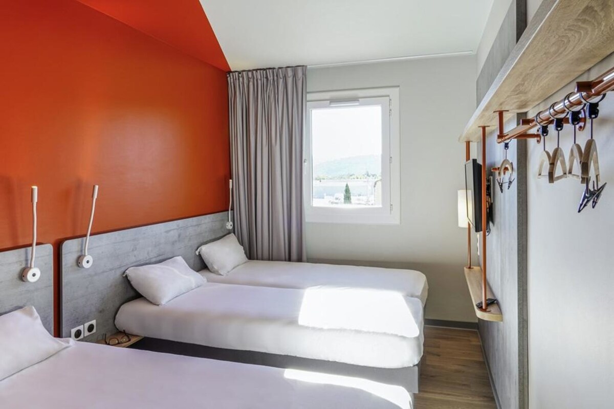 Una habitación de hotel con dos camas, una ventana con vistas y un televisor montado en la pared.