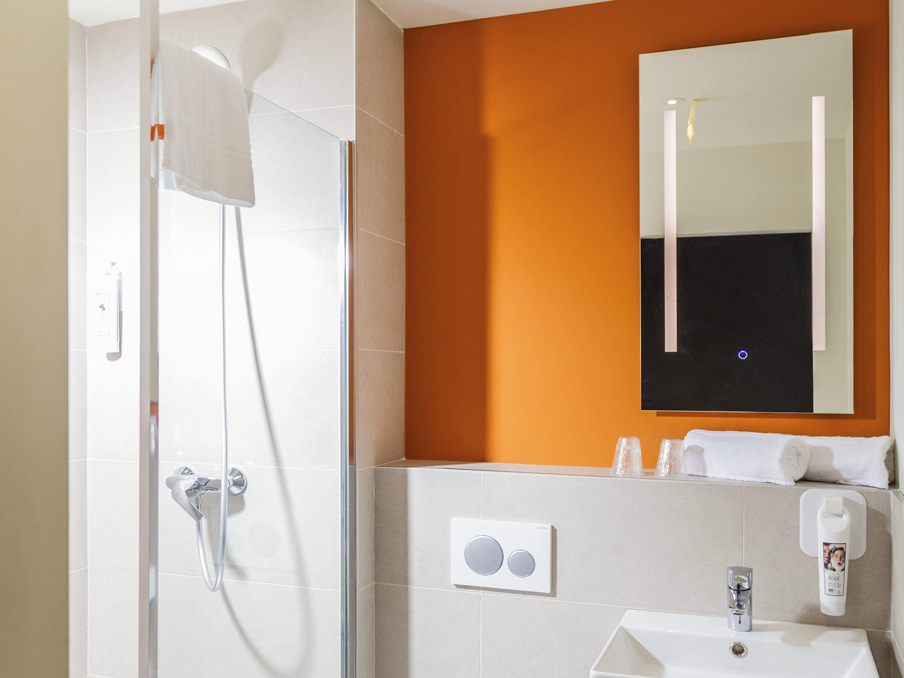 Ein Badezimmer mit Dusche, Waschbecken und Spiegel.