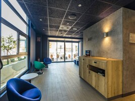 Un interior moderno con una recepción, zona de estar y amplias ventanas.