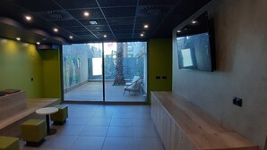 Un interior moderno con una zona de estar, un televisor montado en la pared y vistas al exterior.