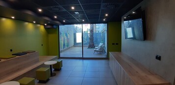Un interior moderno con una zona de estar, un televisor montado en la pared y vistas al exterior.