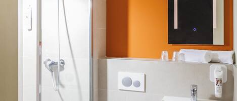 Un baño moderno con cabina de ducha de vidrio, un lavabo blanco y un espejo encima.