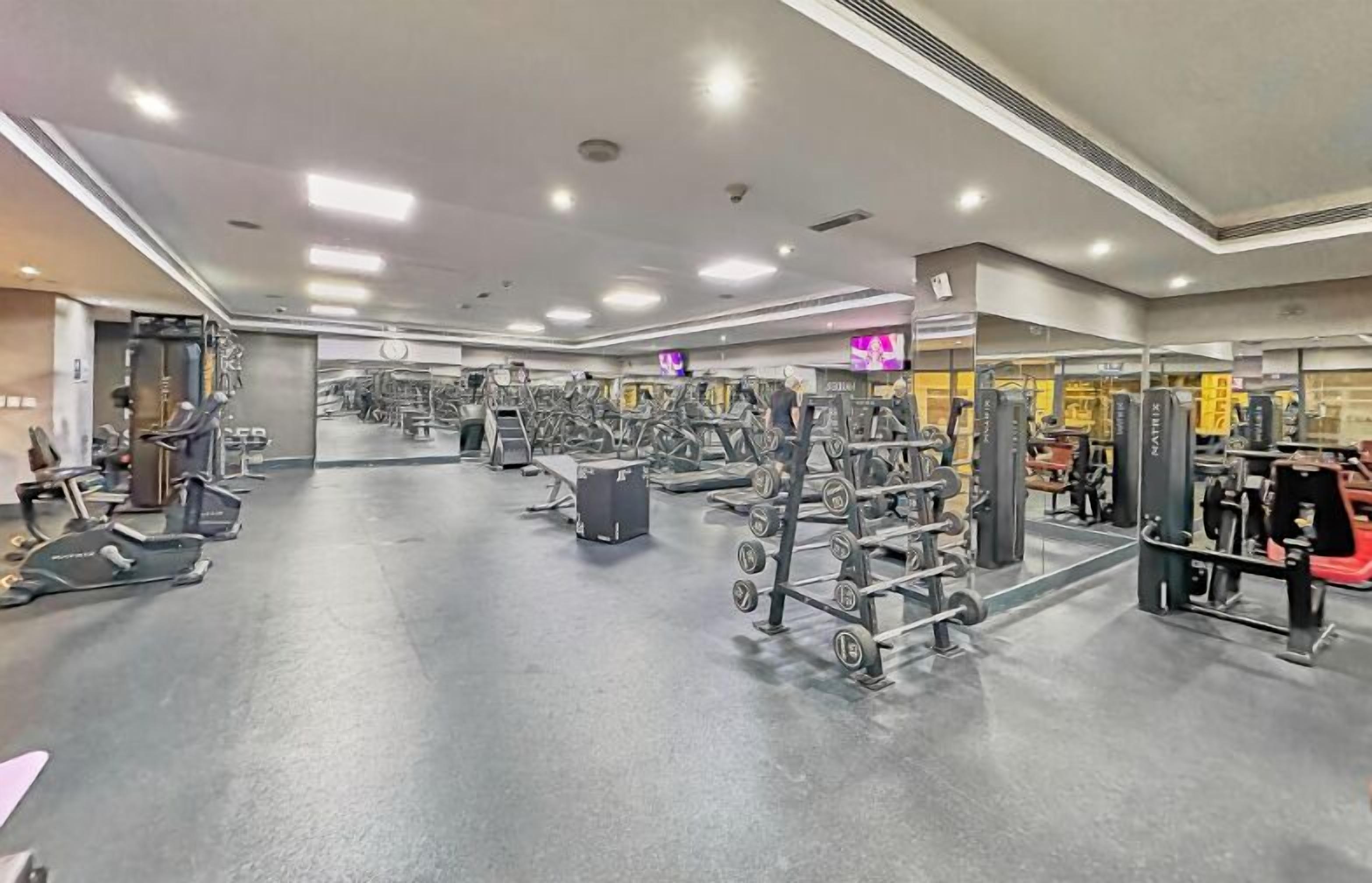 A gym with various exercise equipment, including treadmills, weight machines, and dumbbells.