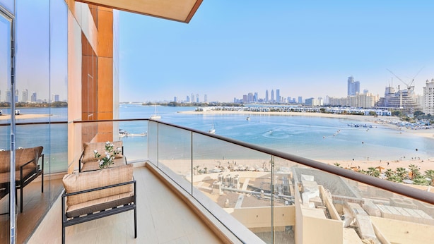 Een balkon met uitzicht op een strand en stadshemelbeeld.