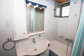 Appartement | Badkamer | Een bad, een haardroger, handdoeken, shampoo