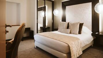 Una habitación de hotel con una cama grande, mesitas de noche, una silla y un espejo.