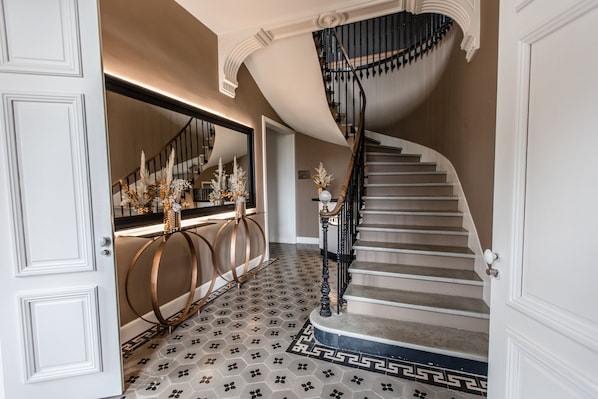 A grand staircase with a black balustrade, a mirror above, and a patterned floor. - Domaine d'en Fargou (Saint-Sulpice)