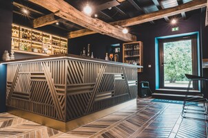 Una zona de bar con techo de madera, mostrador con diseño y estantes llenos de botellas.