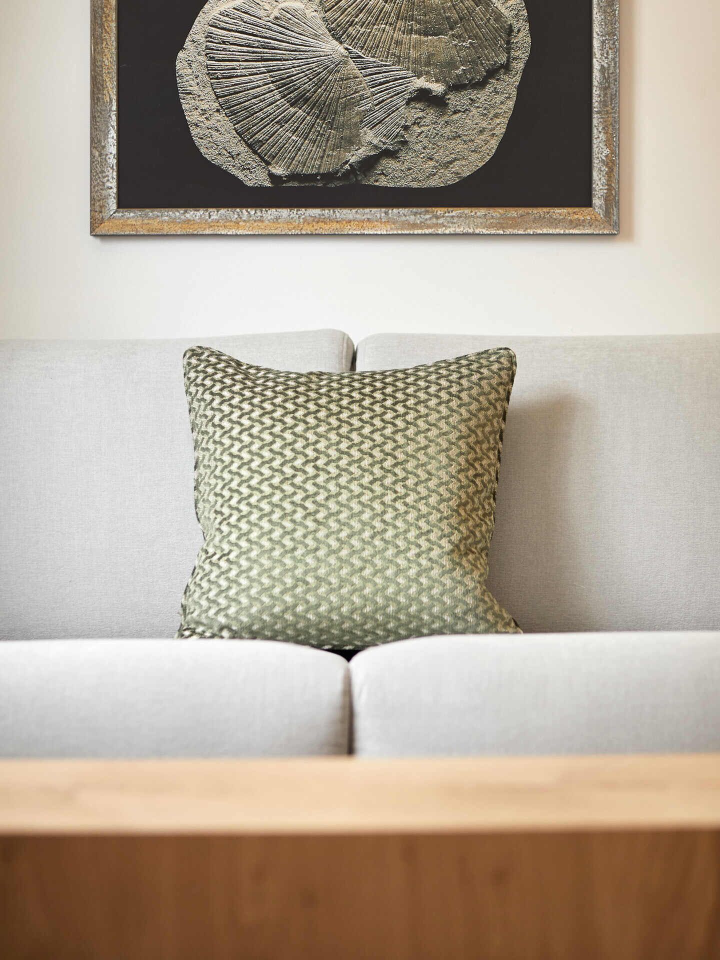 A sofa with a patterned pillow and a framed artwork above it.