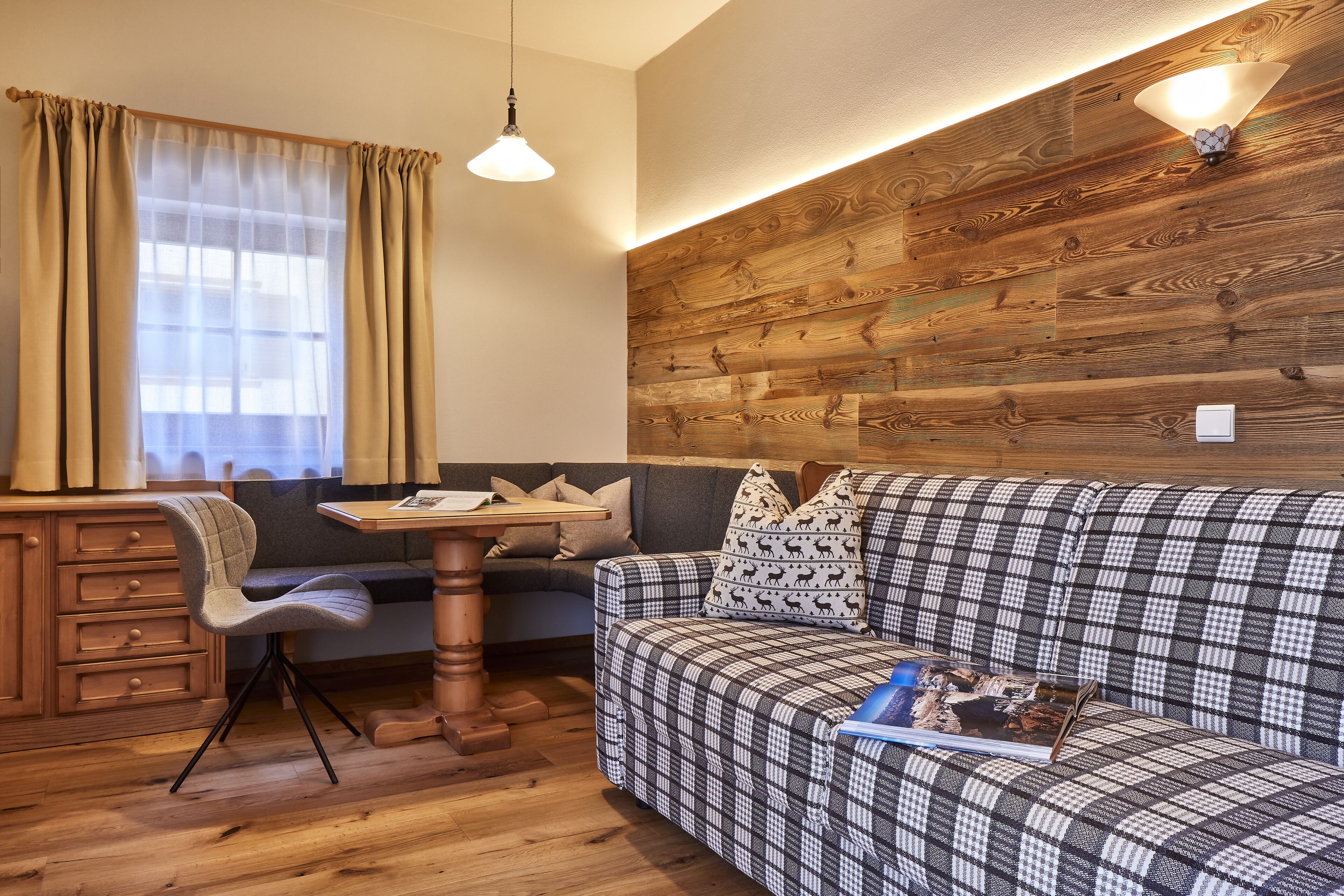 Une pièce chaleureuse avec un mur en bois, un canapé, un bureau et une chaise.