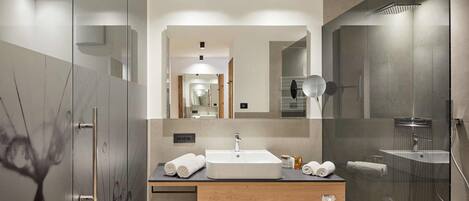 Ein modernes Badezimmer mit einem großen Spiegel, einem Waschbecken und einer Dusche.